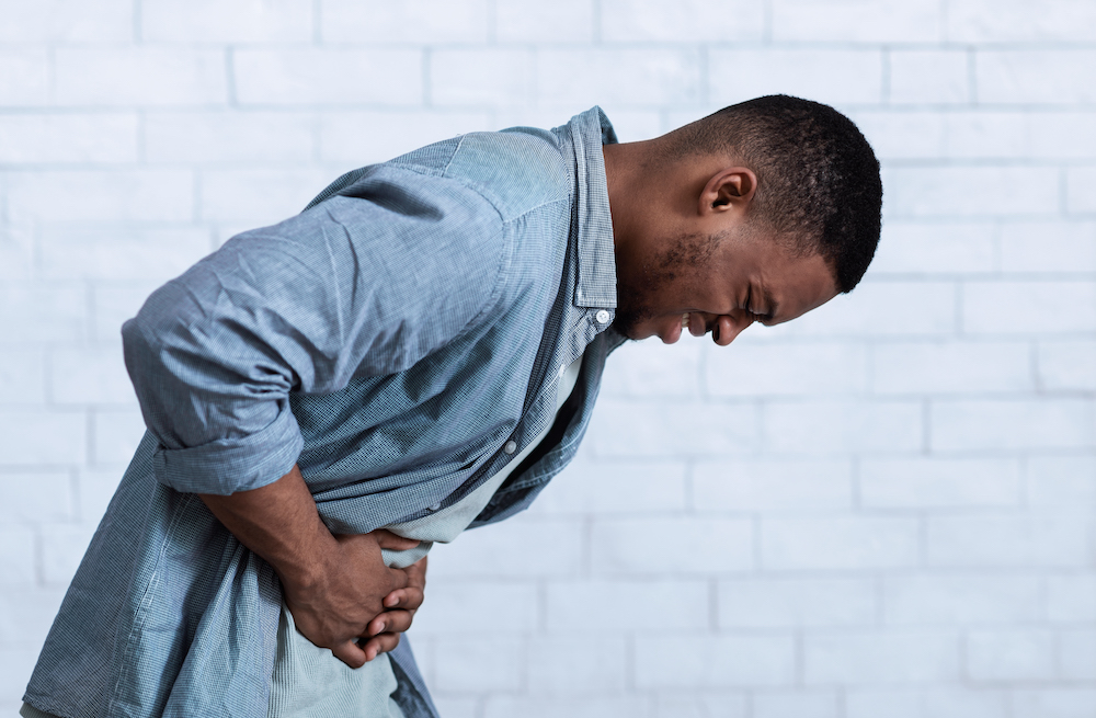 black man hunched over in abdominal pain from ulcerative colitis