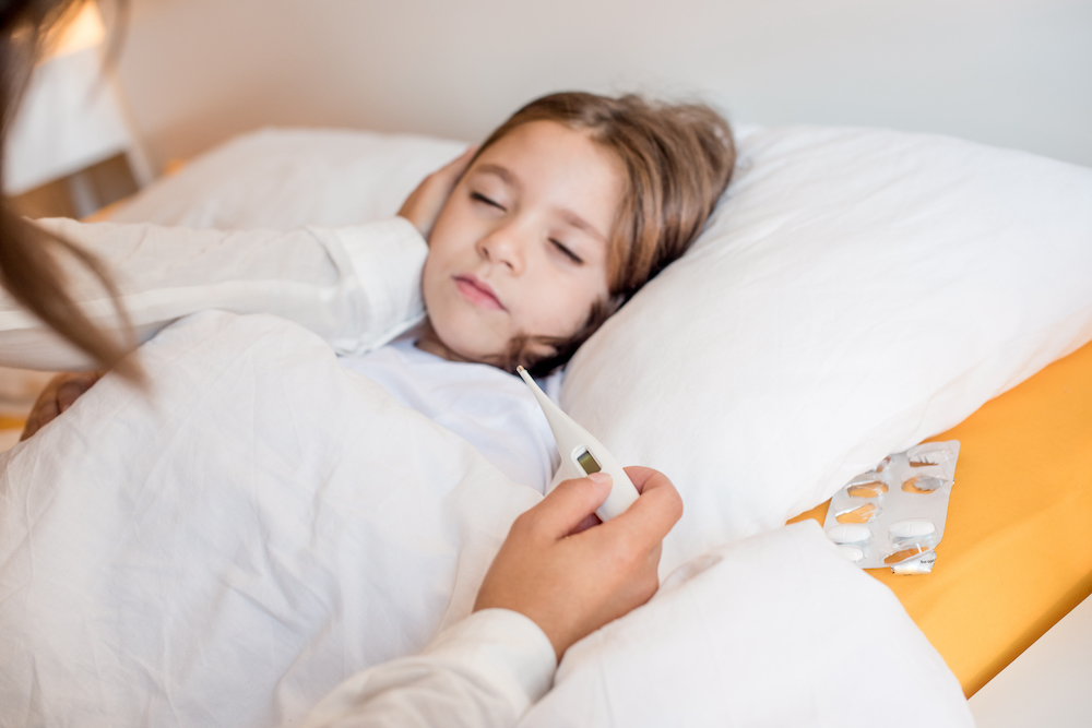 Mother taking care of her sick daughter in bedroom