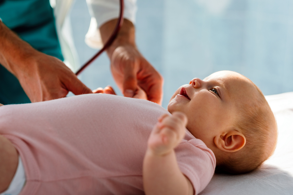 Happy pediatric doctor exams little baby. Health care, medical examination, people concept