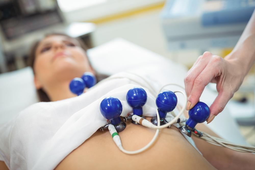 Doctors hand attaching sensors on the patient for electrocardiogram test heart health