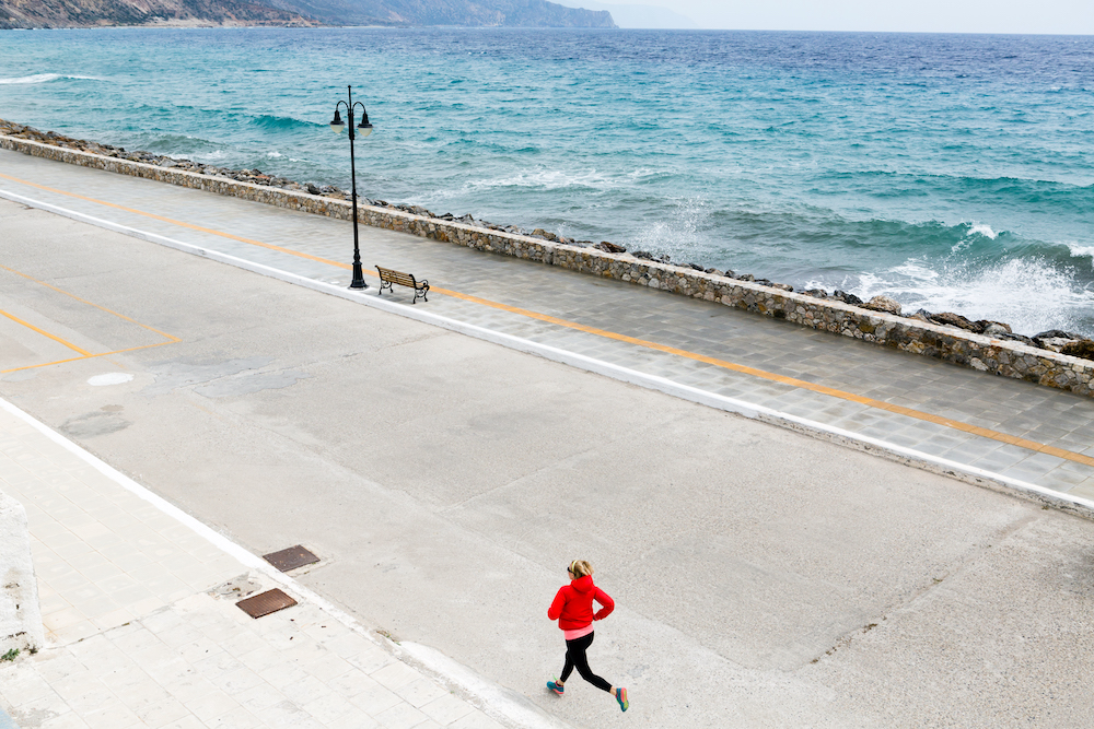 Happy girl running on city street at seaside. Young athlete training and doing workout in urban scene. Sport and fitness inspiration and motivation. Vintage tone. heart health