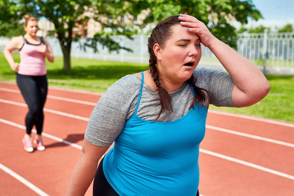 Exhausted runner touching her head with funny facial expression. heat related illness